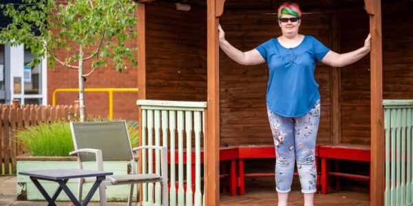 Lucy stands in a garden seating area.