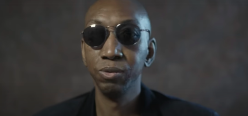 Dike Okoh, a black man wearing dark sunglasses, looking serious
