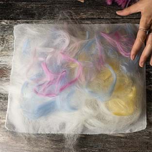 Image shows the wool tops with shades of pink, blue and yellow in swirly patterns.