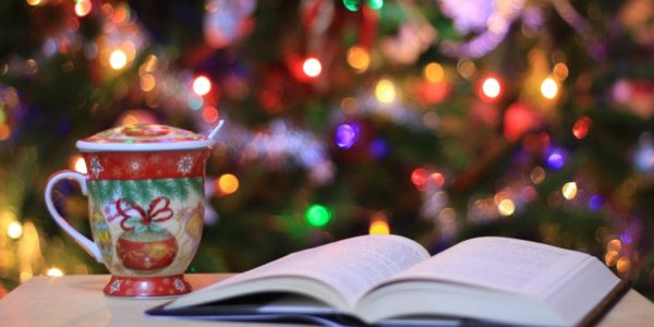A Christmassy scene with a mug and an open book with a Christmas tree in the background