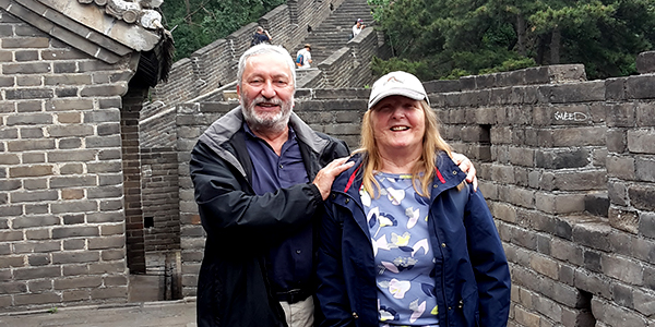 A man and a woman standing in front of the Great Wall of China