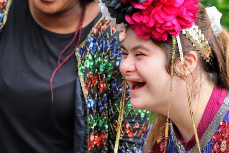 A young woman and her Sense Buddy wearing sparkly festival outfits and laughing.