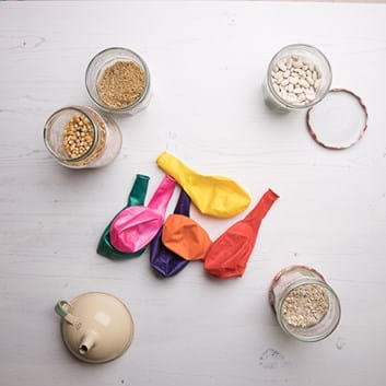 Pots of dried grains to fill balloons, some colourful balloons and a funnel