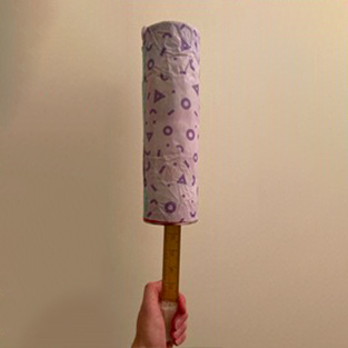 Tube guitar decorated with white paper with purple shapes.