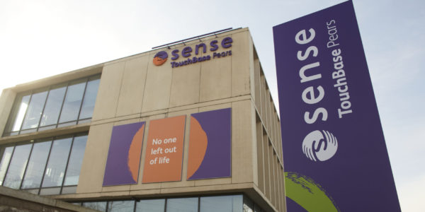 An exterior view of a large building with a purple sign saying Sense TouchBase Pears.