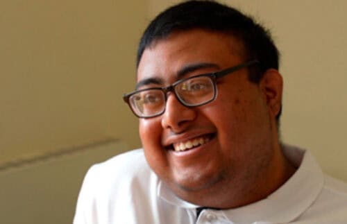 Saihan, a young man in a white teeshirt with short black hair smiling