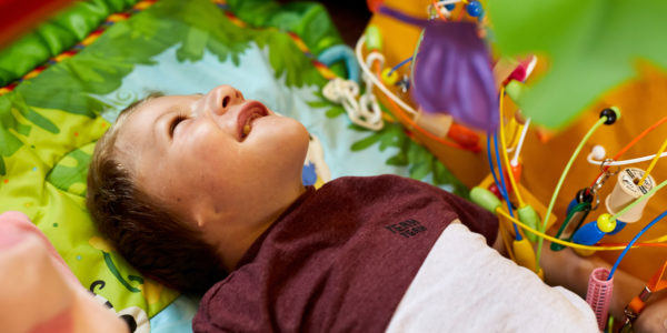 A young child smiling while lying on a play mat.