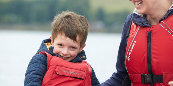 Close-up of a young boy in a lifejacket on a sailing boat.