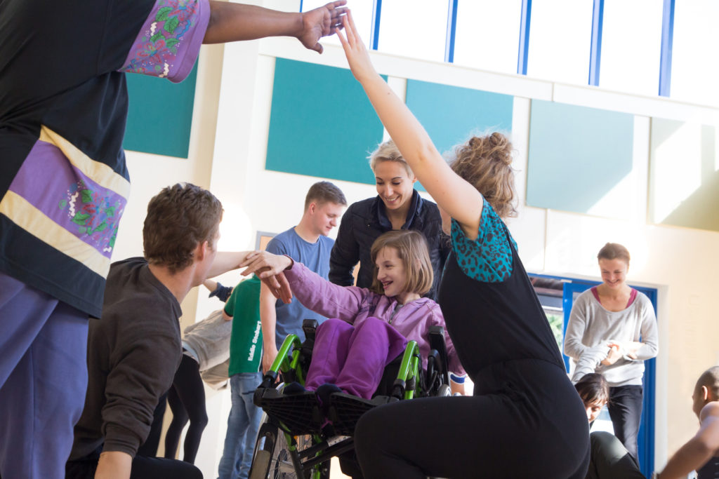 a girl in a wheelchair is dancing with 4 other people