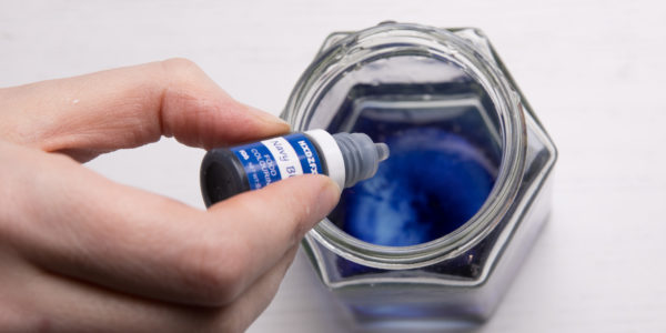 Adding blue dye to a jar of water