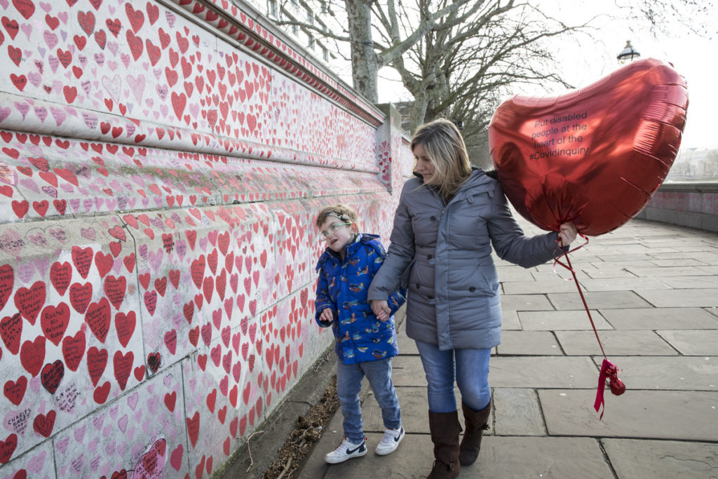 Claire Reece and her 13-year-old son Hugo hold a heart-shaped balloon as they look at the National Covid Memorial Wall in London. 