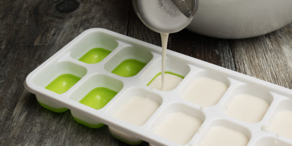 Drizzling a white liquid carefully into an ice-cube tray