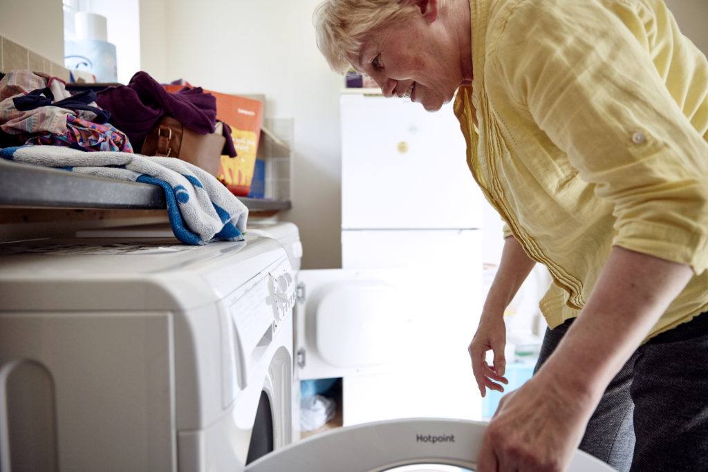 Lin Wallace, a supported living tenant, loading a washing machine.