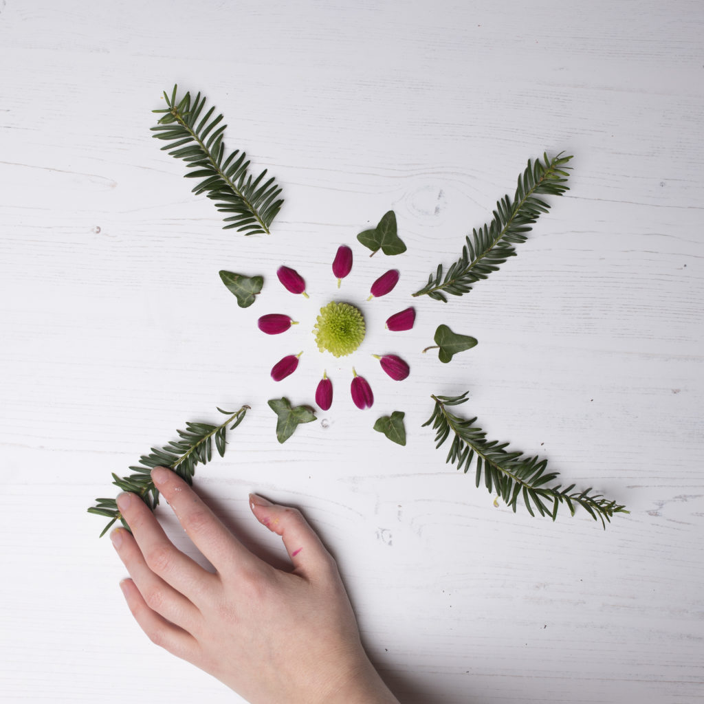 A hand arranging foliage into a pattern