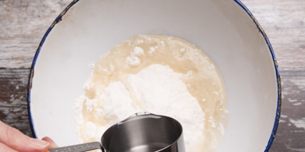 Adding melted coconut oil to a bowl with flour / --