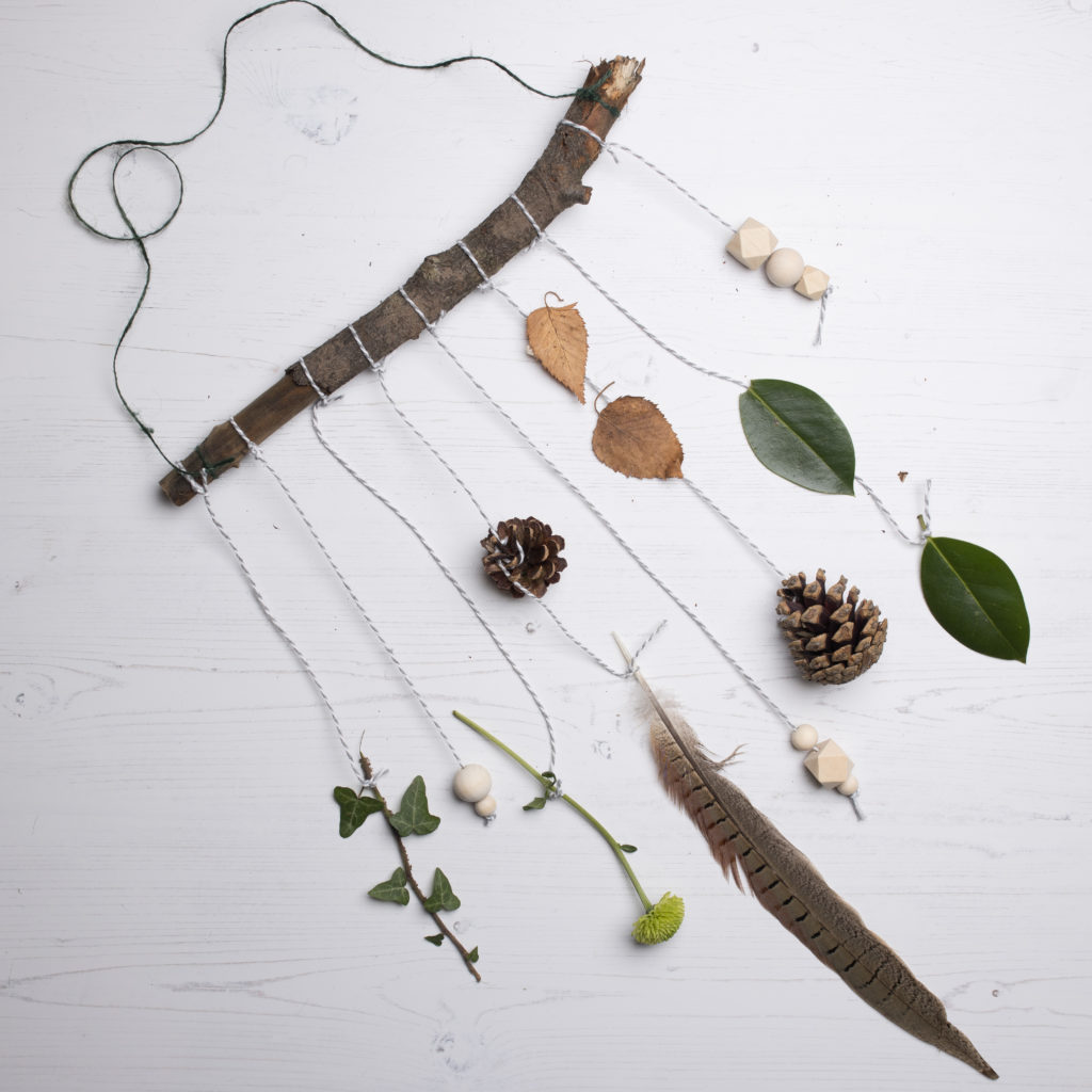 A hanging mobile with natural items like leaves and feathers