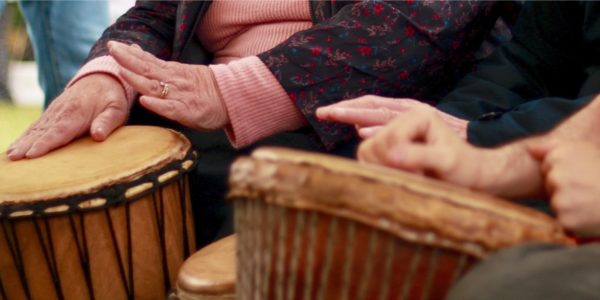 A close up photo of 2 peoples hands drumming on a bongo drum