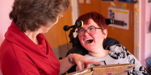 Sally, a white woman with short hair, smiling while communicating with her intervenor.