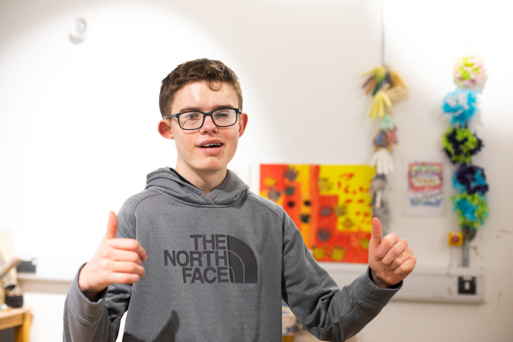George Cook, a white teenage boy wearing a hoodie and glasses, giving a double thumbs up.
