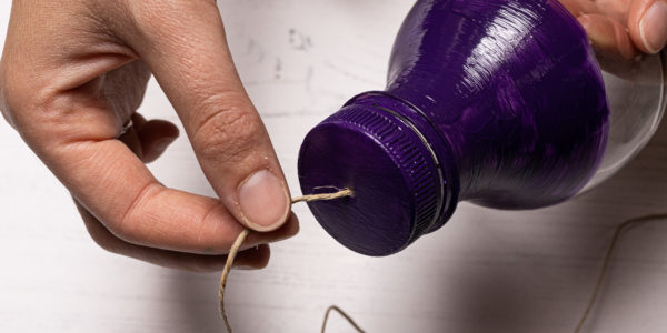 Image shows string being threaded through the bottle cap