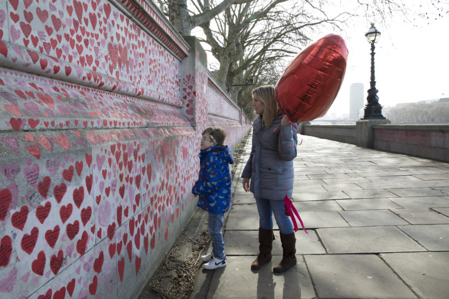 A boy and a woman look at red hearts painted on a wall