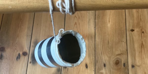 Tin can tied to wooden broom handle with the end of the string.