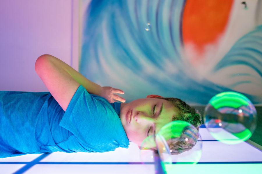 Boy relaxing in multi-sensory room with bubbles.