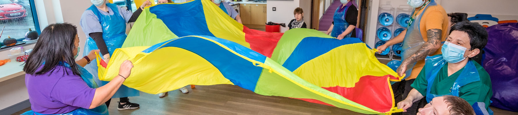 A group of people playing with a parachute at Sense Caerphilly.