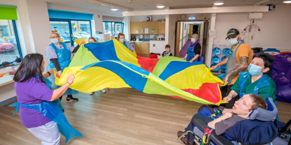 A group of people playing with a parachute at Sense Caerphilly.