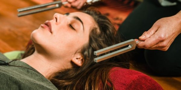 Person lay on the floor during a tuning fork session