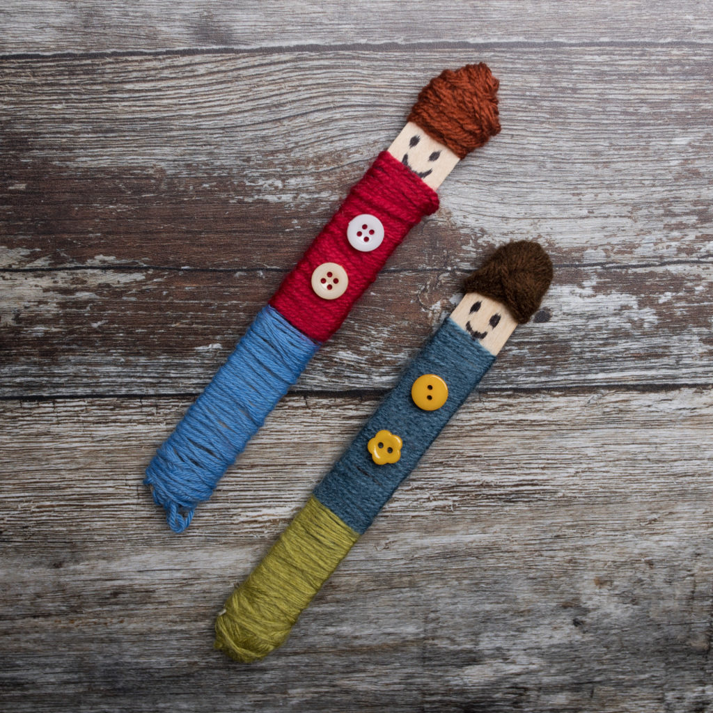 Two smiling worry dolls made of wool and buttons