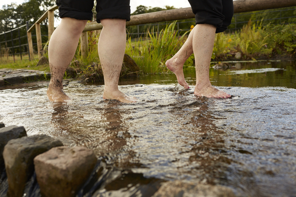 2 people walking in a river barefoot