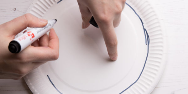 Drawing a circle around a paper plate with a marker