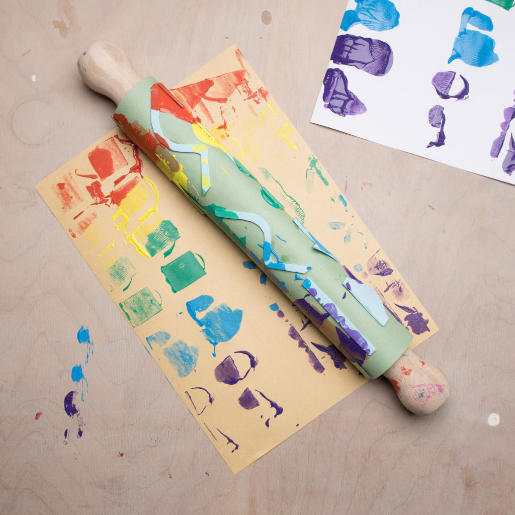 Multicoloured paint marks on a piece of paper with a rolling pin