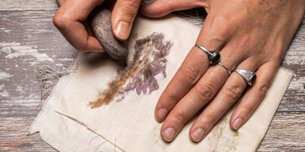 Hand is shown rubbing the stone on the fabric