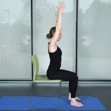 woman sitting on chair with hands raised in air
