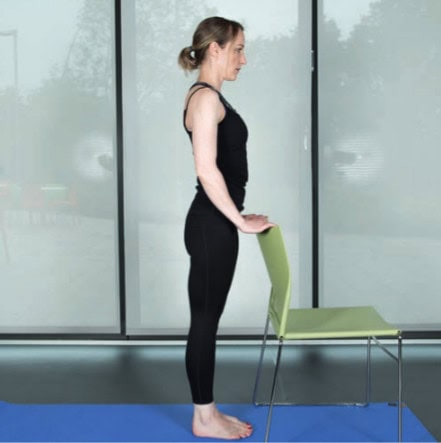 woman standing behind chair