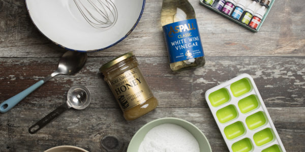 A selection of ingredients for watercolour paints, including vinegar, an ice-cube tray and a whisk