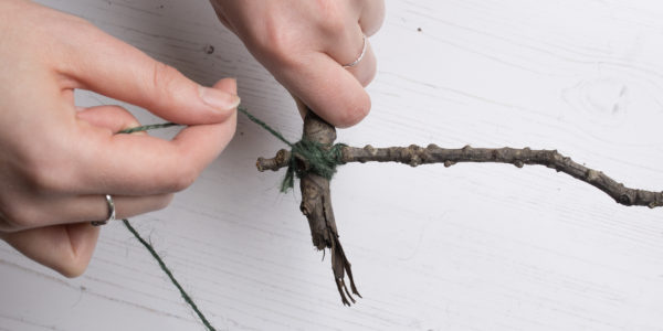 Binding twigs together at the corners with dark green string