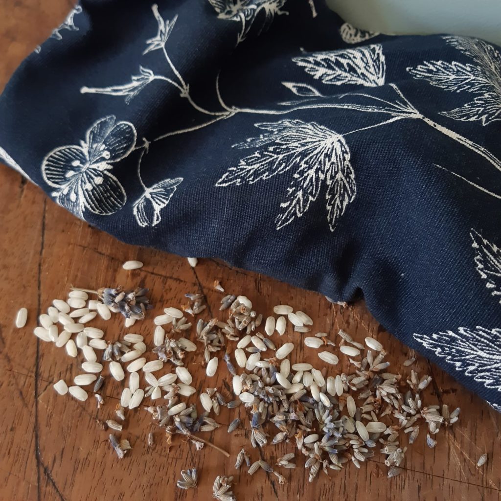A no-sew eye pillow in a navy blue fabric with sprinkles of lavender next to it 