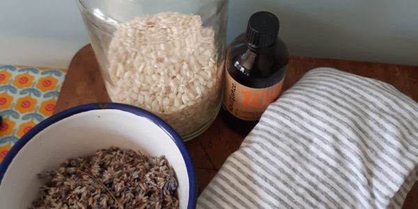 A bowl of lavender, a jar of rice, some striped fabric and a small bottle of essential oils
