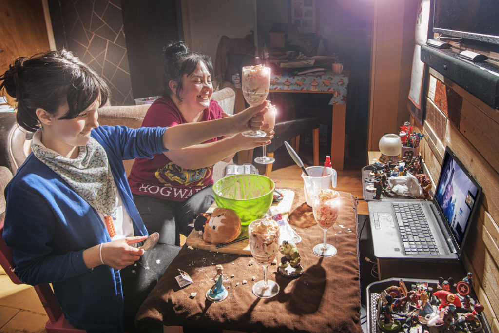 Mother and daughter hold homemade ice cream  in front of laptop screen