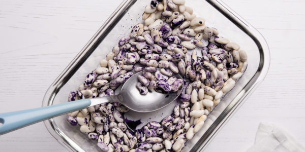 Mixing the purple-white beans with a spoon in a small glass dish