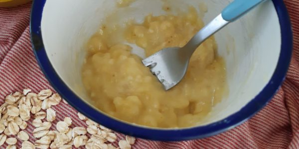 A yellowy, mashed up banana and honey mix in a bowl with a fork