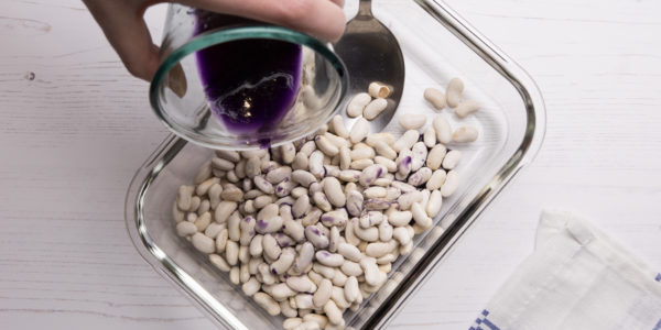 Adding scented purple liquid to the beans