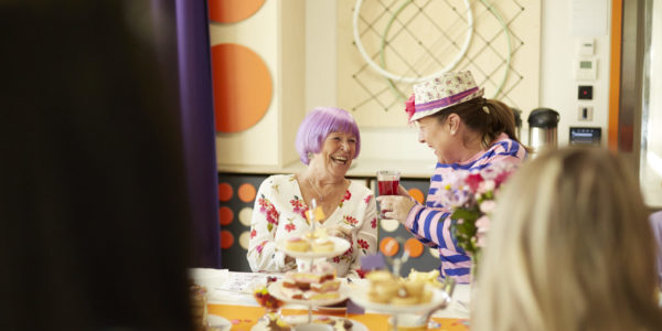 Two women enjoy a cup of tea while laughing.