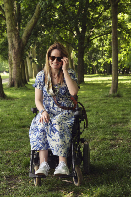 A woman, Karen, in a wheelchair on the grass in Regent's Park, in front of some trees