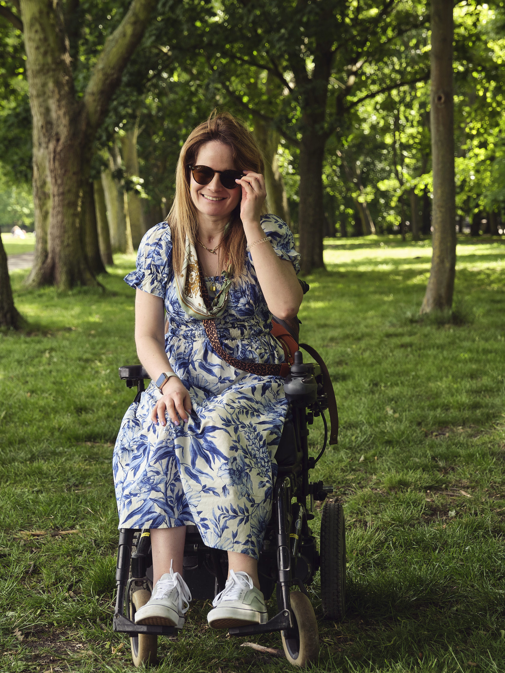 A woman, Karen, in a wheelchair on the grass in Regent's Park, in front of some trees