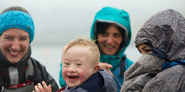 A family in the rain with a little boy smiling in the foreground