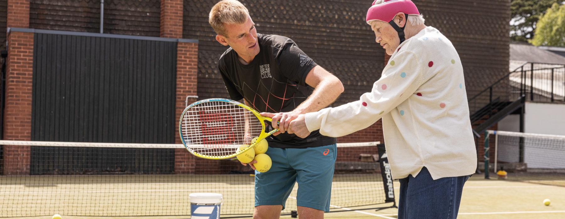 a man helps a woman by showing her how to hold a racket